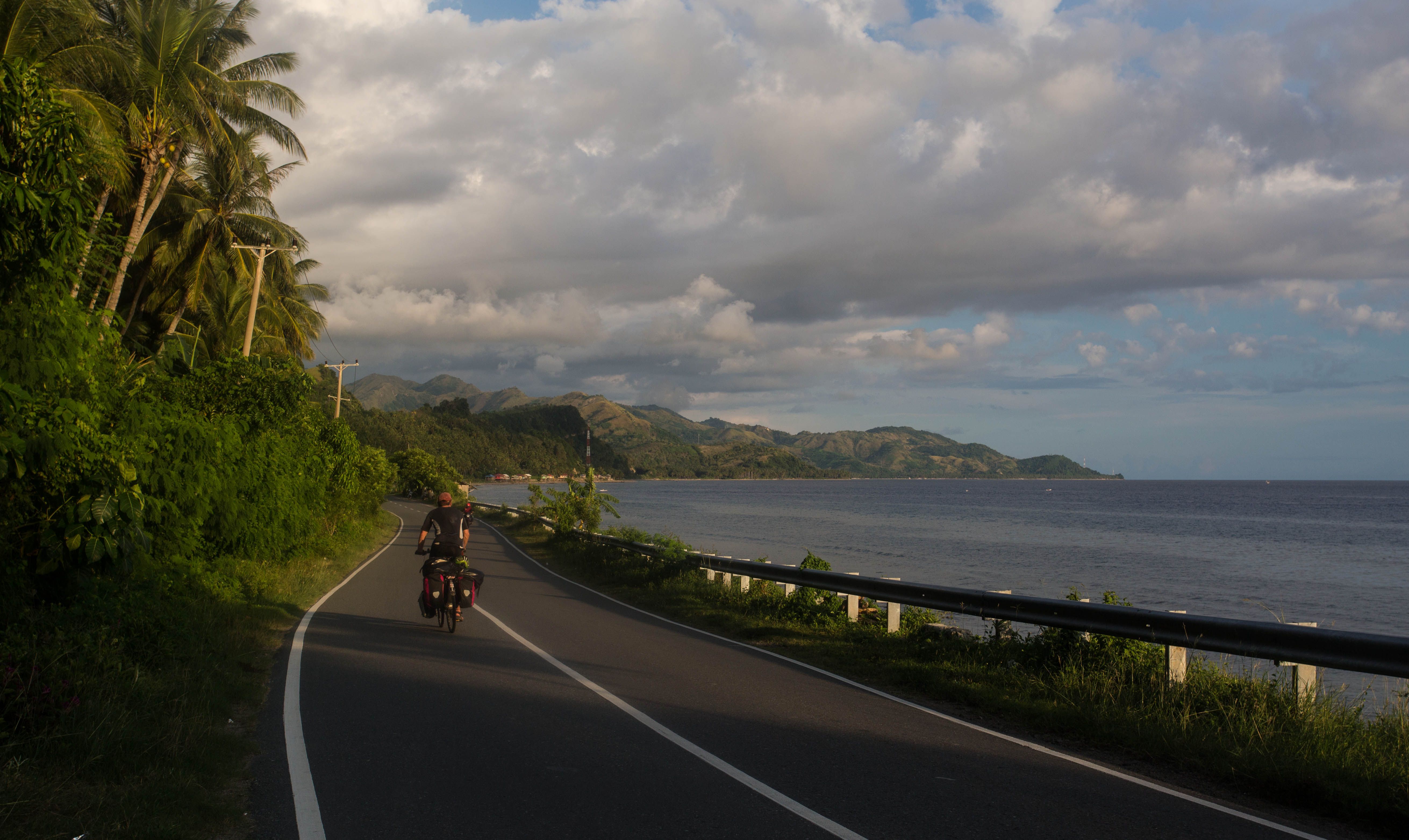 The sun setting as Matthew pedals southwards along the Sulawesi coast near the village of Somba