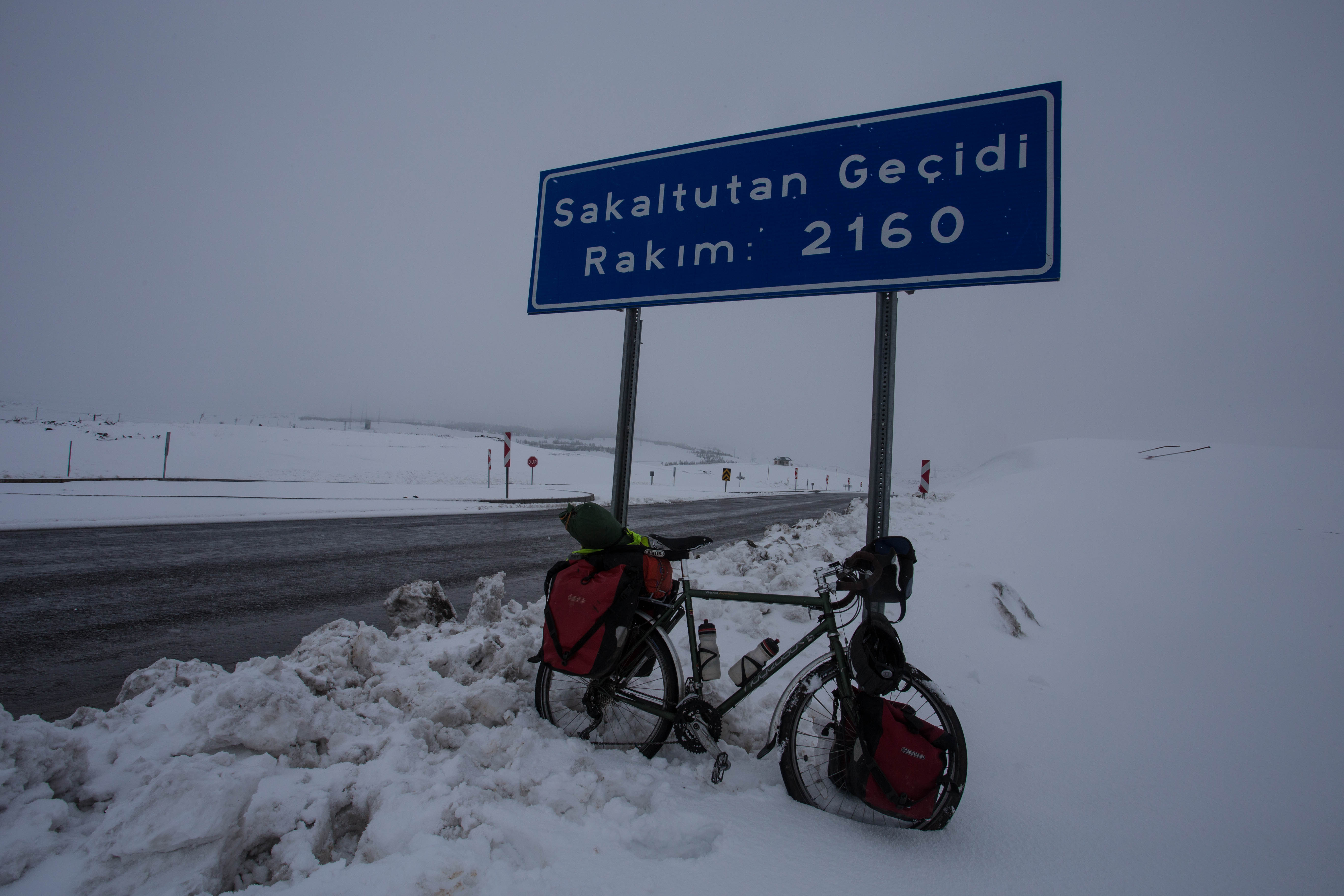 Lifting my bike into the snow for the obligatory summit photo
