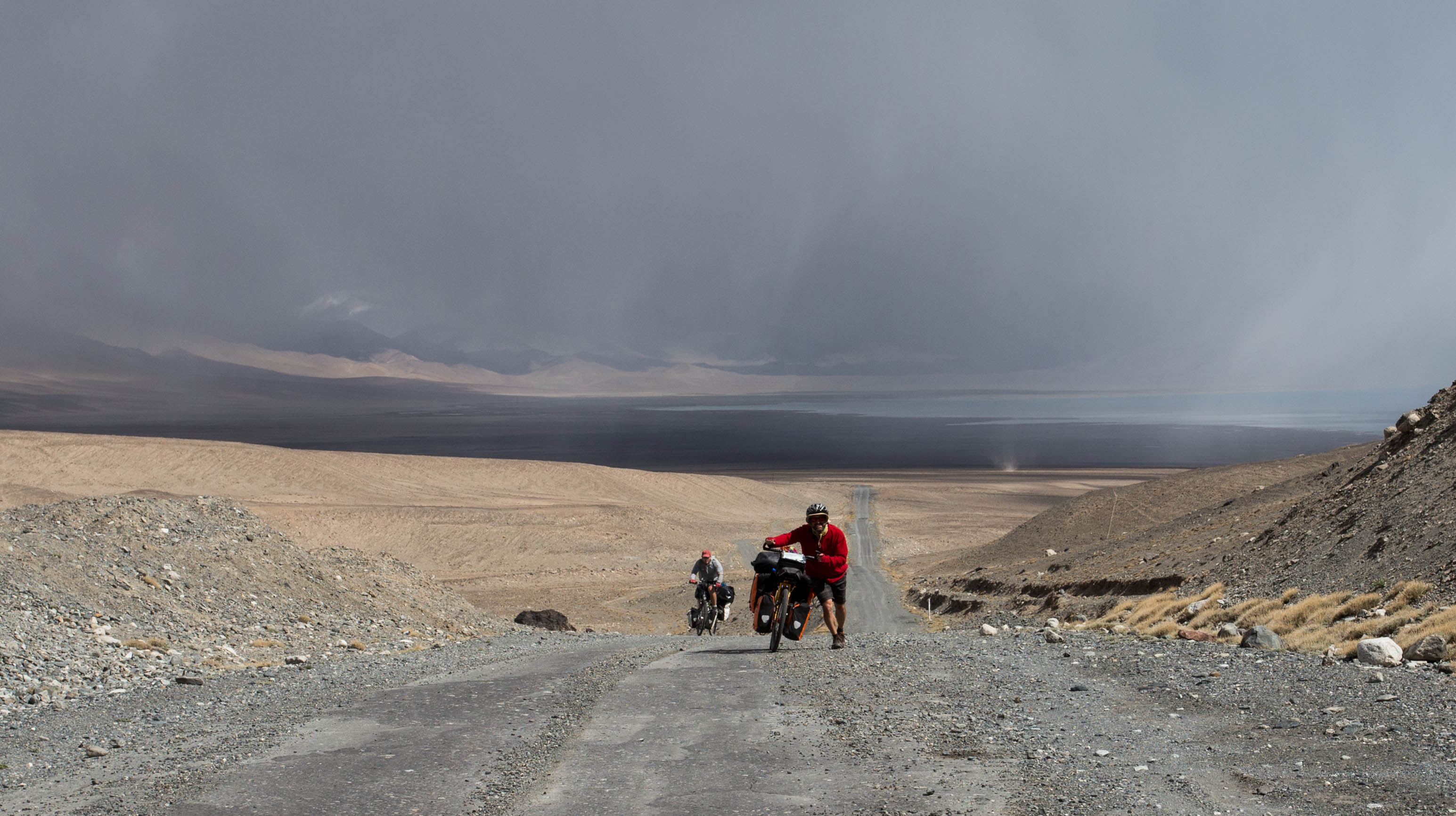 Mark and Matthew fighting up the first pass out of Karakul with a dust devil and some ominous clouds in the background