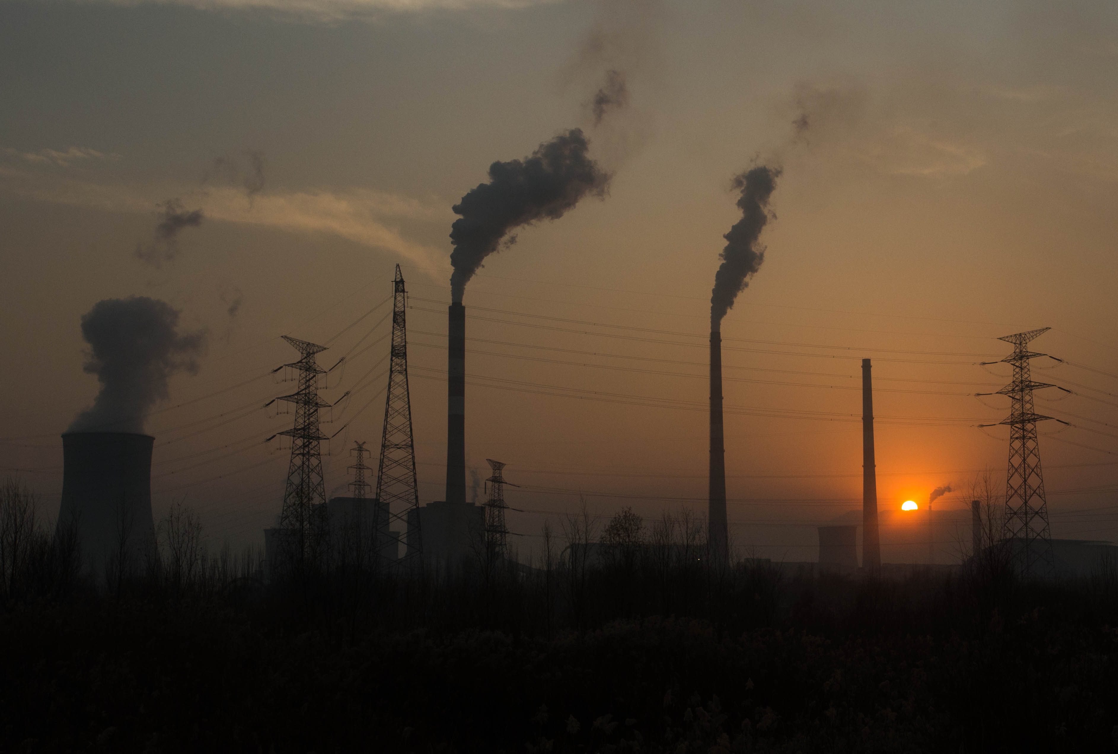 The sun dipping beneath the horizon behind the thick smog of Lanzhou