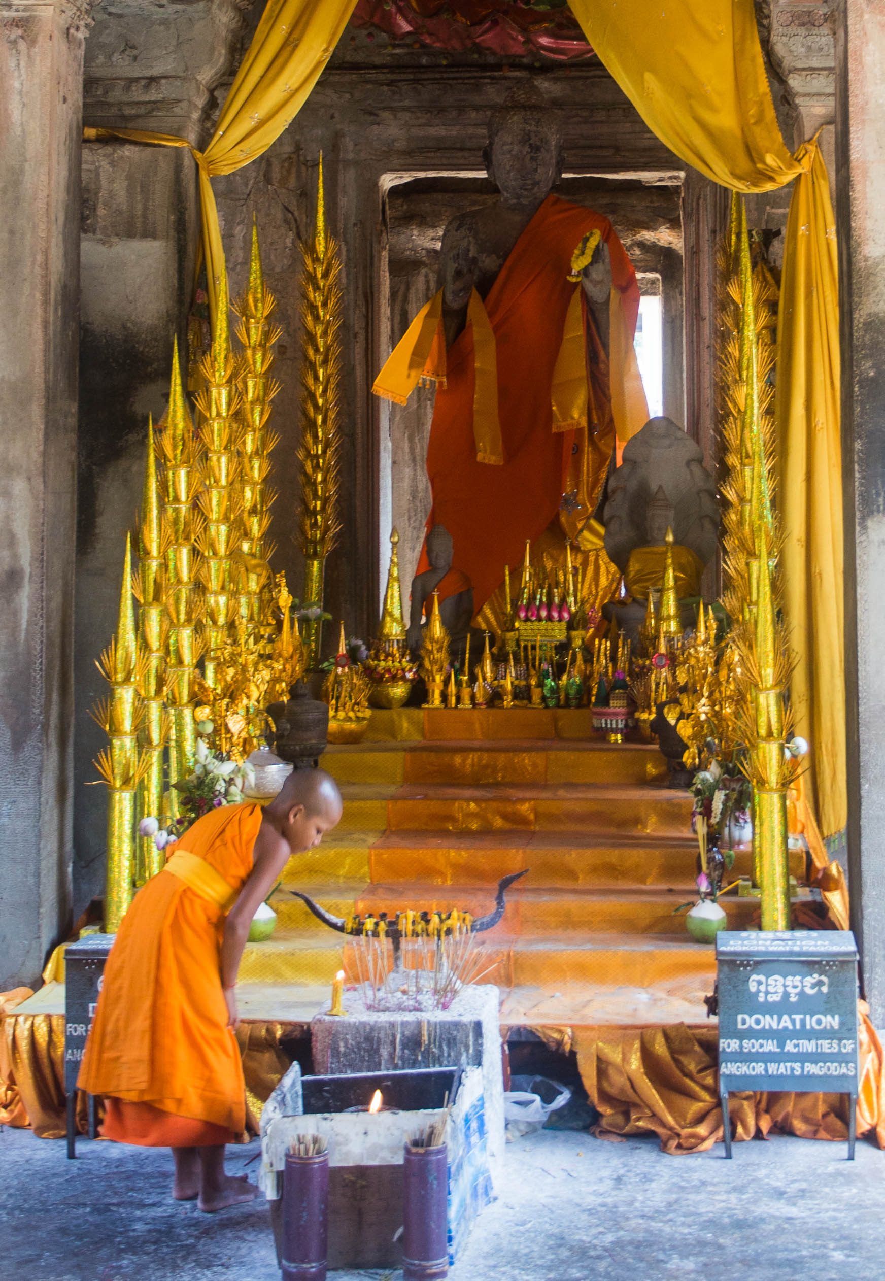 A young monk overlooking the burning of incense in Angkor Wat, Cambodia