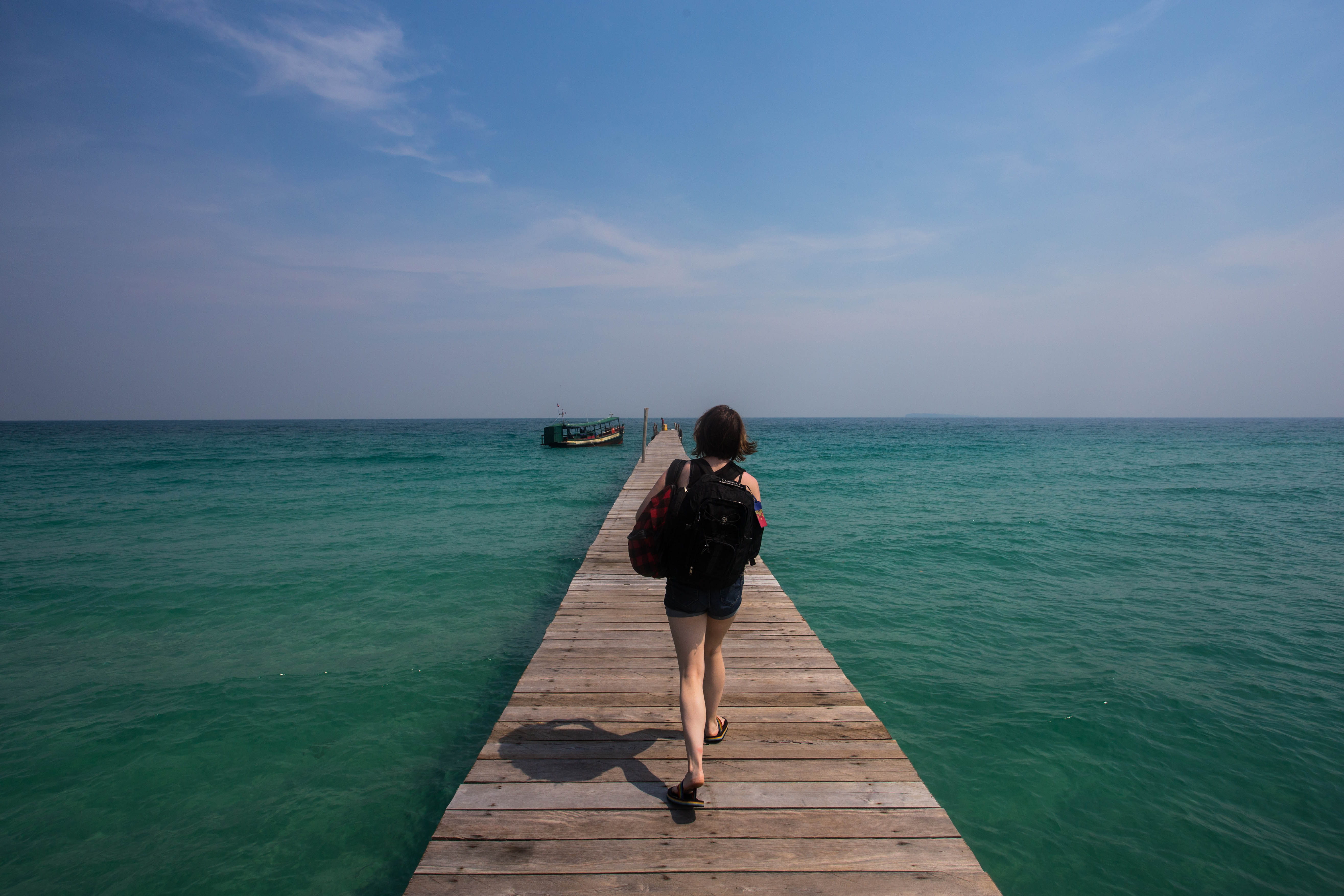 Elana reluctantly walking towards the boat that would take us away from this idyllic beach-side resort